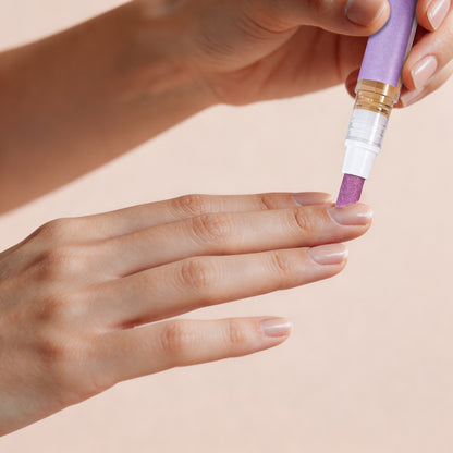 Close-up of hand using nail oil pen applicator on cuticle area for precise nourishment